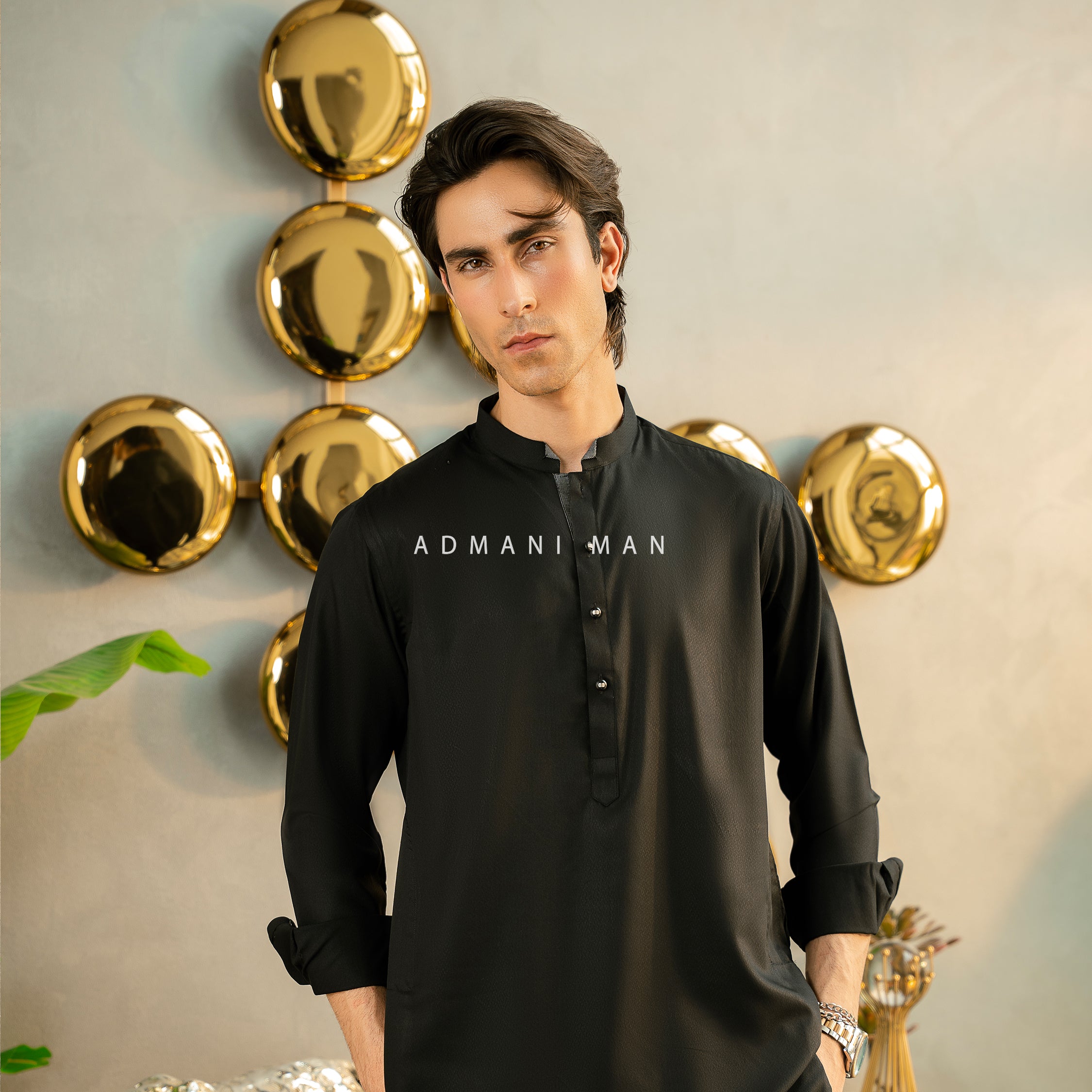 Premium black unstitched kurta by Admani Man - Menswear shalwar kameez fabric for Pakistani men in a luxury setting.