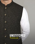 Admani premium unstitched menswear waistcoat fabric in a dark textured patterned weave paired with a white shalwar kameez.